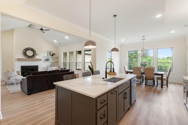 kitchen with a kitchen island with sink, a glass covered fireplace, a sink, and light wood finished floors