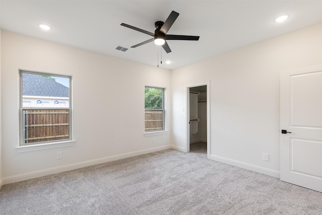 unfurnished bedroom with visible vents, baseboards, a walk in closet, recessed lighting, and carpet