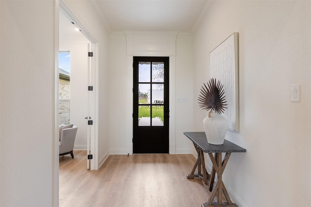 doorway to outside featuring crown molding, baseboards, and light wood-style flooring