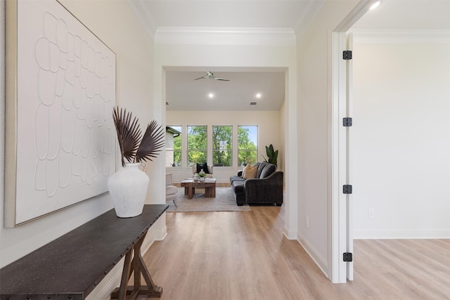 hallway with baseboards, ornamental molding, and light wood-type flooring