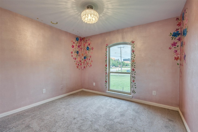 carpeted spare room with an inviting chandelier and baseboards