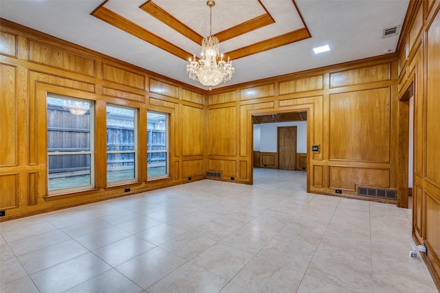 unfurnished room featuring a tray ceiling, an inviting chandelier, and visible vents
