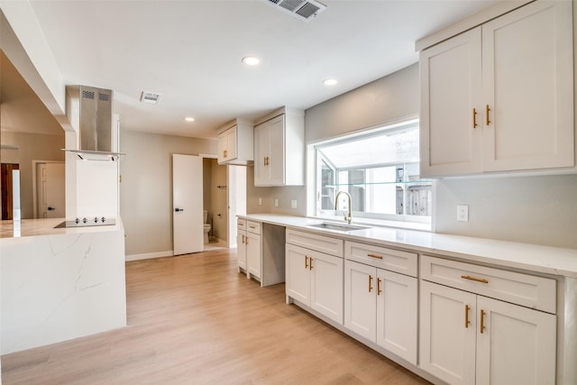 kitchen featuring light stone countertops, black electric stovetop, a sink, light wood-style flooring, and visible vents