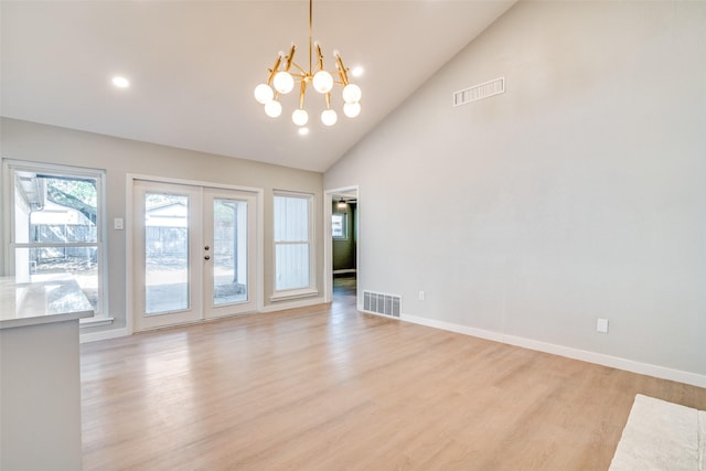 empty room featuring a chandelier, baseboards, visible vents, and light wood finished floors