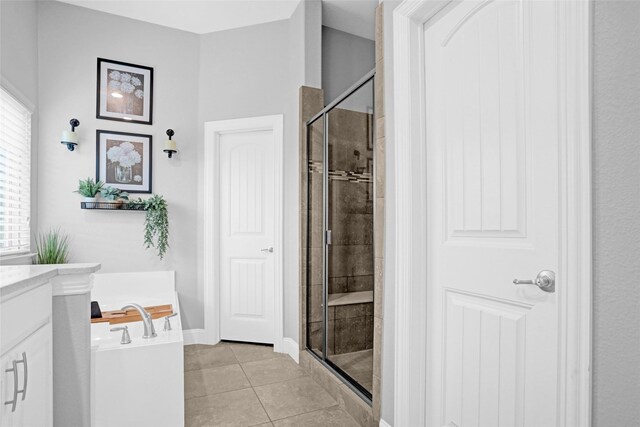 full bathroom featuring a shower stall, tile patterned floors, baseboards, a bath, and vanity