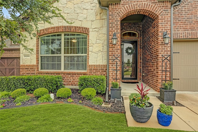 view of exterior entry with brick siding, stone siding, and a garage