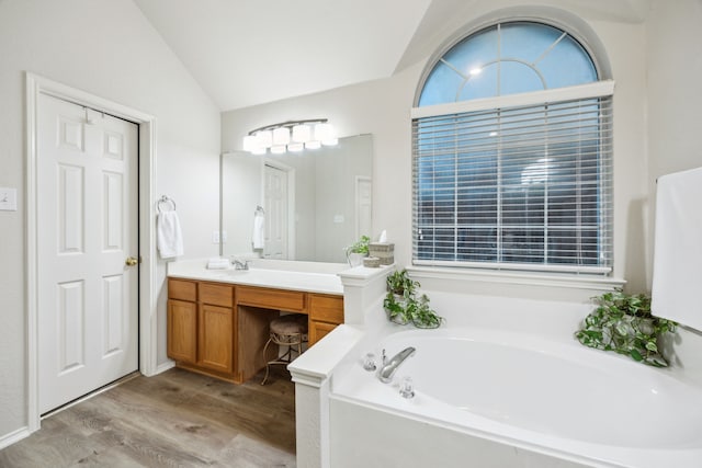 full bath with a bath, wood finished floors, lofted ceiling, and vanity
