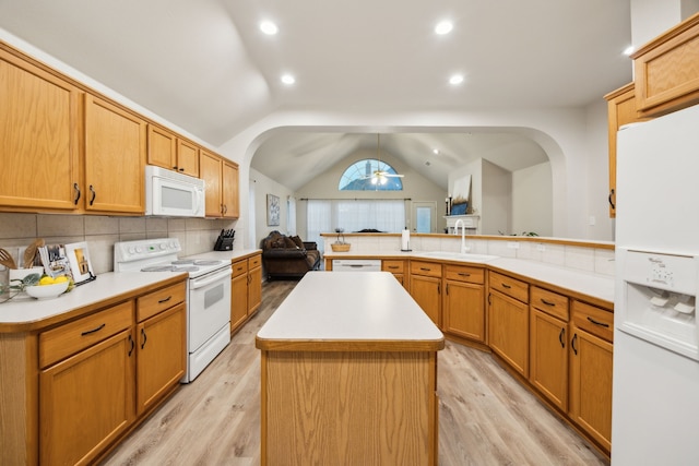 kitchen featuring a sink, a peninsula, white appliances, tasteful backsplash, and arched walkways