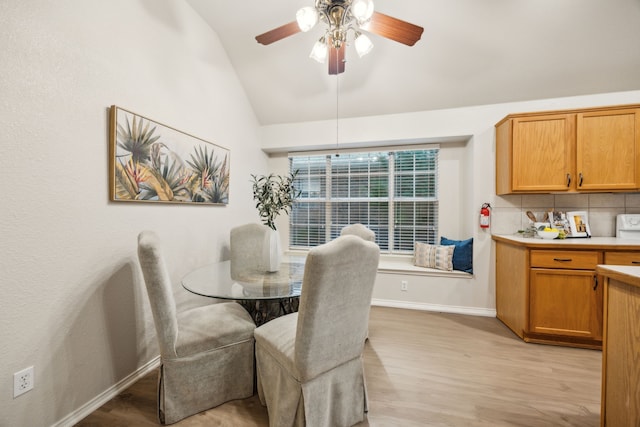 dining space featuring baseboards, a ceiling fan, light wood-style flooring, and vaulted ceiling