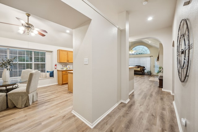 corridor with baseboards, arched walkways, and light wood-style flooring