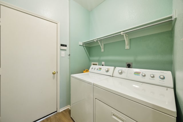 clothes washing area featuring laundry area, baseboards, washing machine and dryer, and wood finished floors