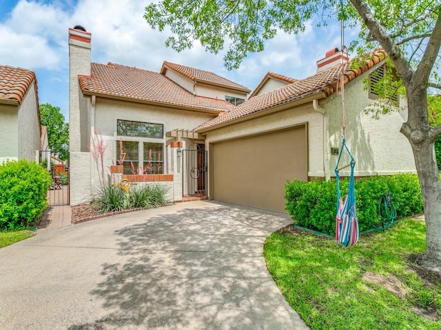 mediterranean / spanish home with an attached garage, driveway, a chimney, and a gate