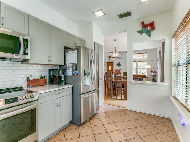 kitchen with a healthy amount of sunlight, appliances with stainless steel finishes, backsplash, and light countertops