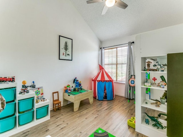game room with wood finished floors, baseboards, a textured ceiling, a ceiling fan, and vaulted ceiling