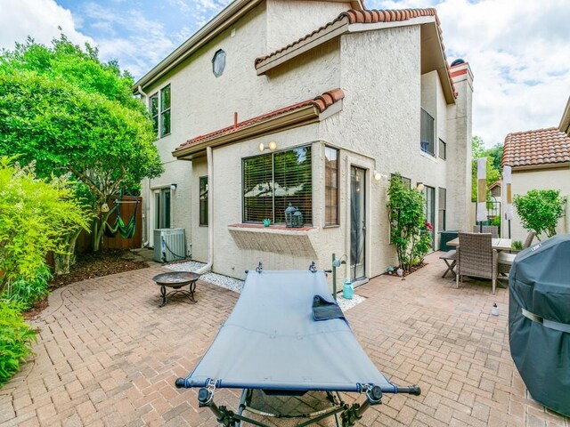 rear view of property featuring central air condition unit, outdoor dining space, a patio area, and stucco siding