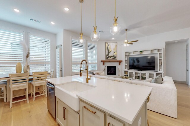 kitchen featuring a ceiling fan, visible vents, dishwasher, a sink, and light wood finished floors