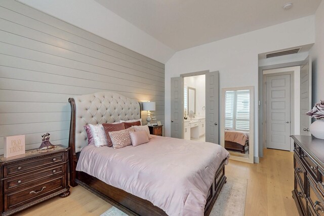 bedroom with visible vents, connected bathroom, light wood-style flooring, and vaulted ceiling