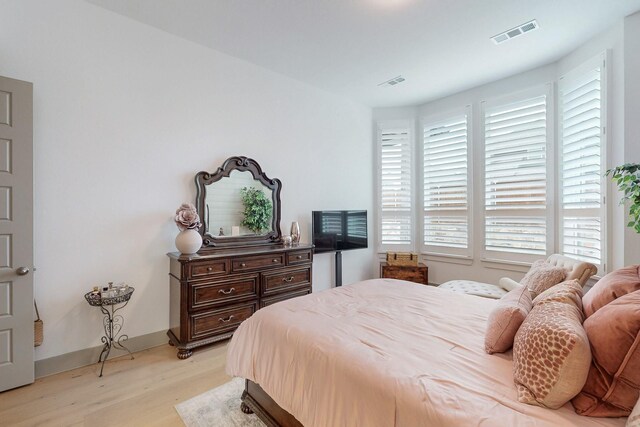 bedroom with light wood-style floors, baseboards, and visible vents