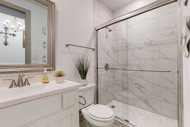 bathroom with toilet, an inviting chandelier, a shower stall, and vanity