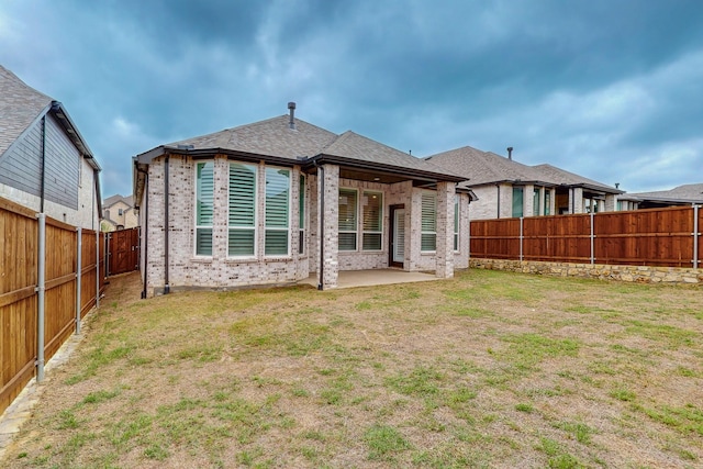 back of house with a fenced backyard, a lawn, a patio area, and brick siding