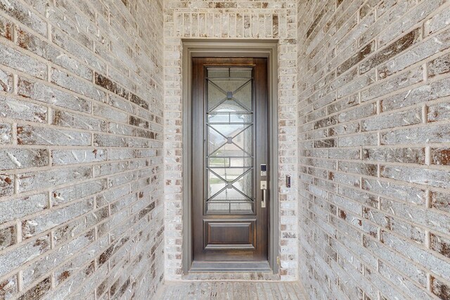 view of exterior entry featuring brick siding