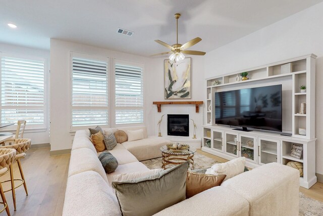 living area with a ceiling fan, visible vents, plenty of natural light, and wood finished floors