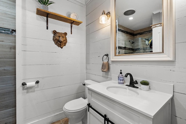 full bathroom featuring vanity, wood walls, walk in shower, and toilet