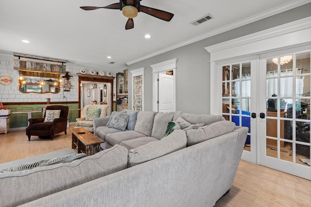 living area with crown molding, visible vents, french doors, and wood finished floors