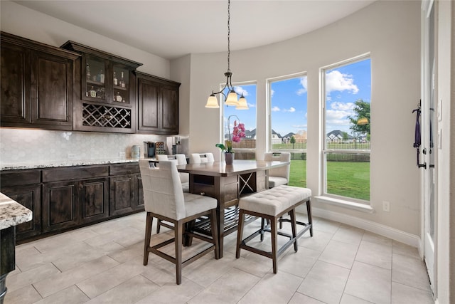 2308 Topaz Dr, Rockwall, TX 75087 - dining space with baseboards, a notable chandelier, bar, and light tile patterned floors