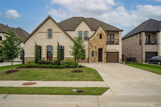 2308 Topaz Dr, Rockwall, TX 75087 - french provincial home featuring a front lawn, stone siding, brick siding, concrete driveway, and an attached garage