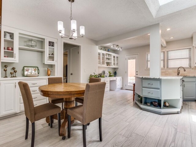 dining area with a textured ceiling, a chandelier, and light wood finished floors
