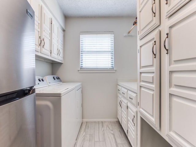 clothes washing area featuring washer and clothes dryer, cabinet space, baseboards, and a textured ceiling