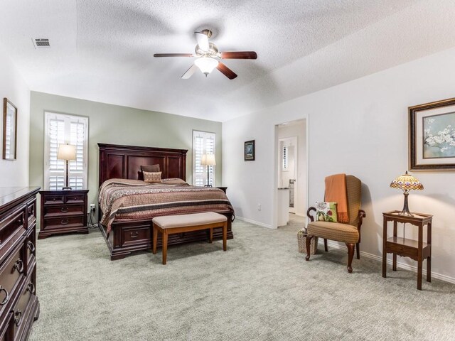 bedroom with light colored carpet, a textured ceiling, baseboards, and a ceiling fan
