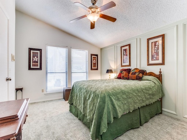 bedroom with vaulted ceiling, a textured ceiling, light colored carpet, ceiling fan, and baseboards