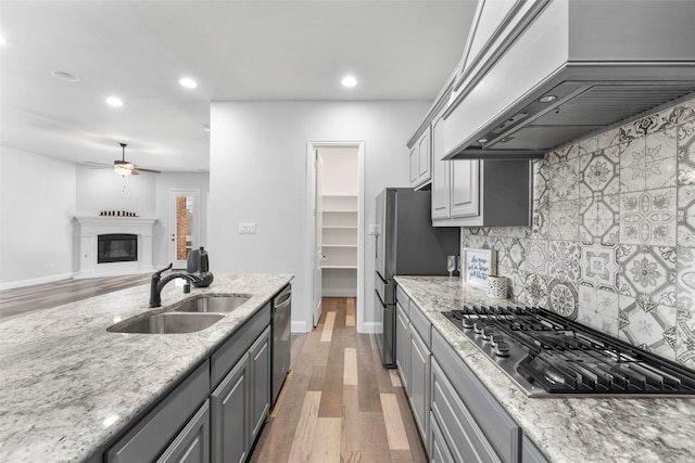 kitchen with a sink, gray cabinets, recessed lighting, custom range hood, and appliances with stainless steel finishes
