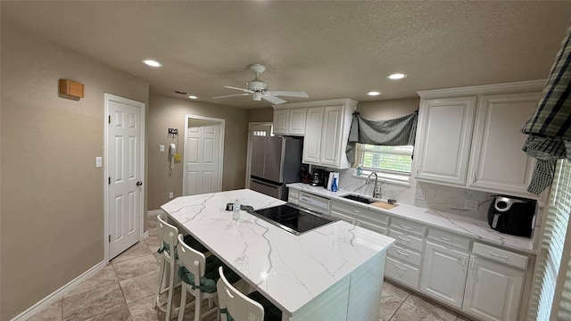 407 S Lakewood Cir, Lake Bridgeport, TX 76426 - kitchen featuring freestanding refrigerator, a sink, black electric stovetop, white cabinetry, and a center island