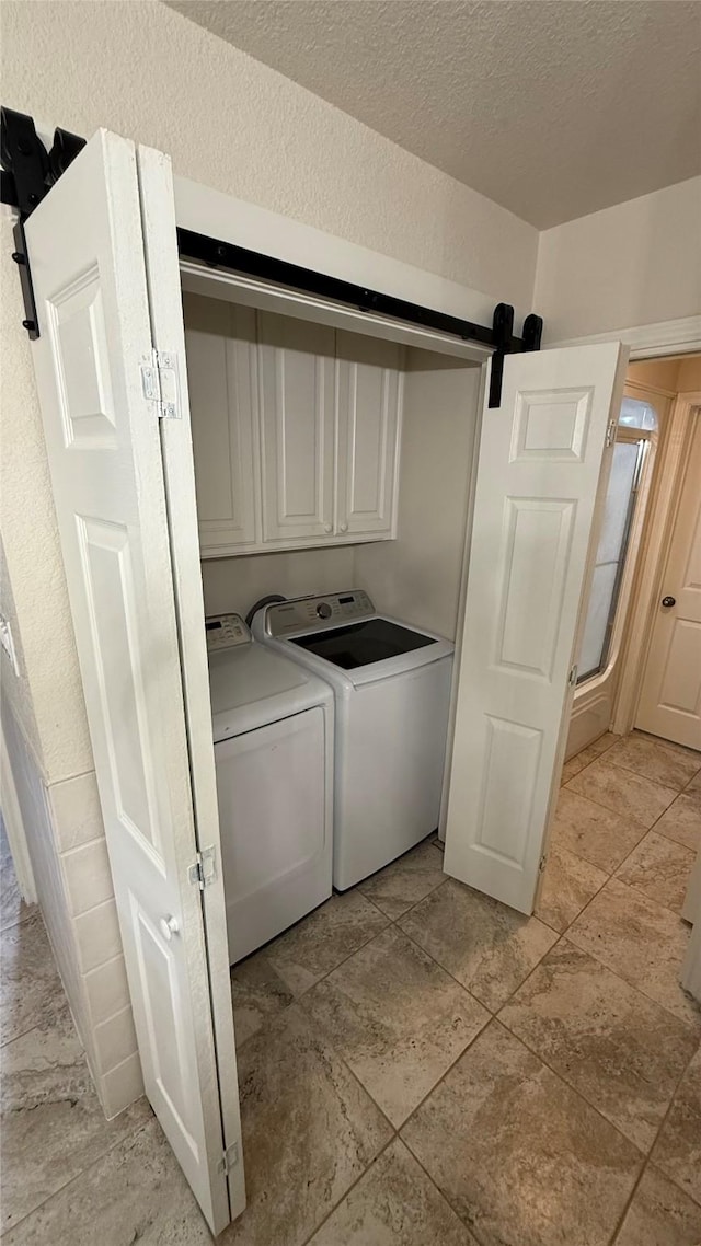 407 S Lakewood Cir, Lake Bridgeport, TX 76426 - washroom with washer and dryer, cabinet space, a barn door, and a textured ceiling