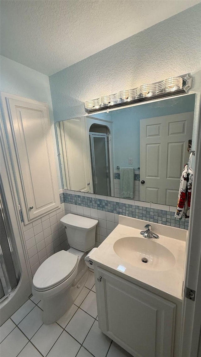 407 S Lakewood Cir, Lake Bridgeport, TX 76426 - bathroom featuring tile walls, tile patterned floors, vanity, toilet, and a textured ceiling