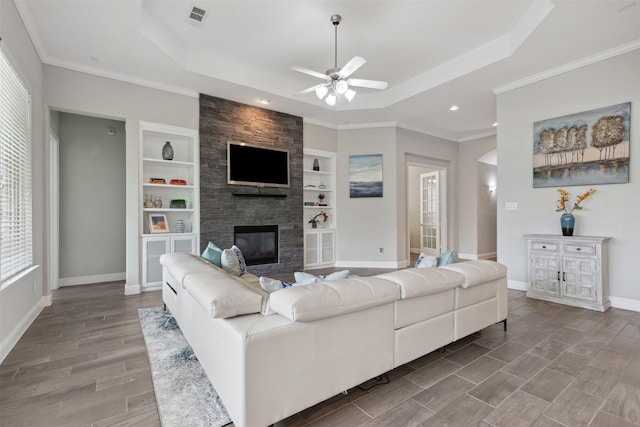 living area featuring a raised ceiling, a ceiling fan, a large fireplace, and visible vents
