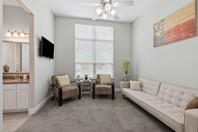 living area featuring baseboards, ceiling fan, and light tile patterned floors