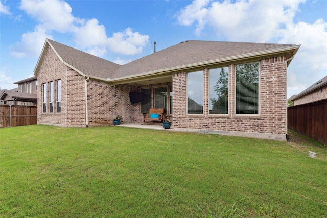 back of property with a lawn, brick siding, a patio, and a fenced backyard