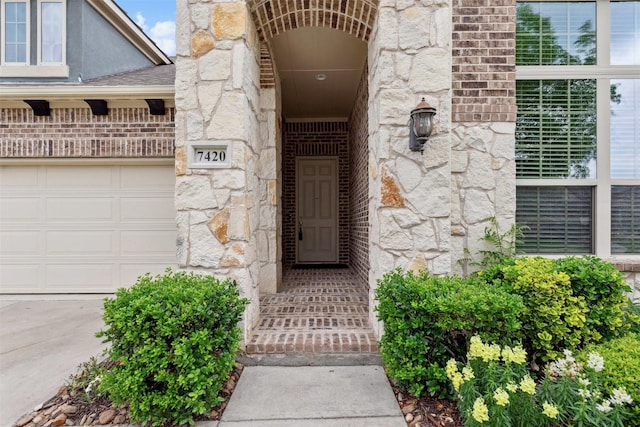 entrance to property featuring an attached garage and stone siding