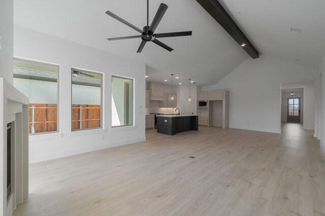 unfurnished living room featuring beam ceiling, ceiling fan, high vaulted ceiling, a sink, and light wood finished floors
