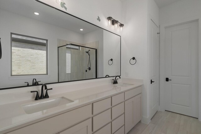 full bath featuring double vanity, recessed lighting, a sink, and a stall shower