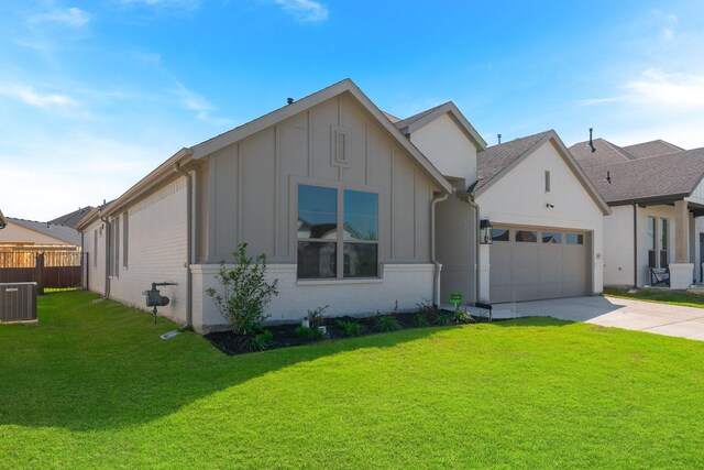 view of front of home with an attached garage, central AC, a front lawn, board and batten siding, and concrete driveway