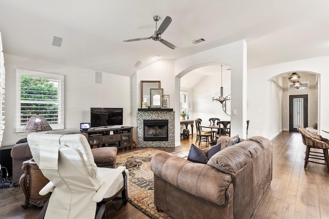 living room with arched walkways, vaulted ceiling, wood finished floors, and ceiling fan with notable chandelier