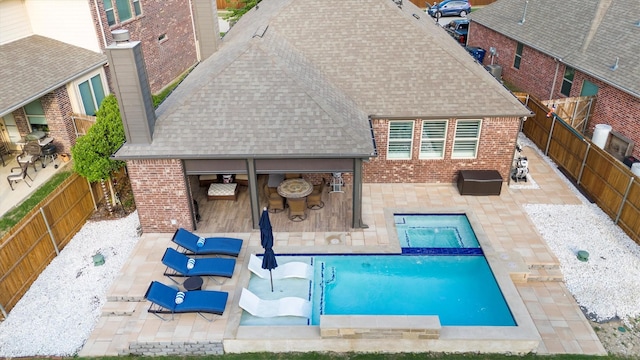 view of pool featuring an outdoor bar, a pool with connected hot tub, a fenced backyard, and a patio area