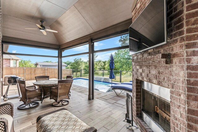 sunroom featuring ceiling fan, outdoor dining space, and an outdoor brick fireplace