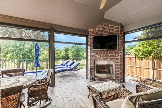 sunroom featuring a healthy amount of sunlight, ceiling fan, and an outdoor living space with a fireplace