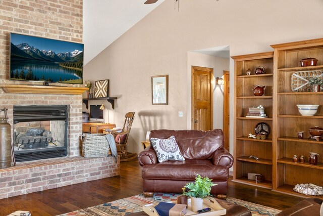 living room with high vaulted ceiling, ceiling fan, a brick fireplace, and wood finished floors